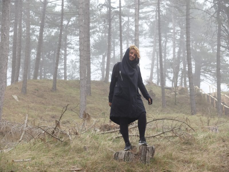 photo of smiling person standing in misty woodland