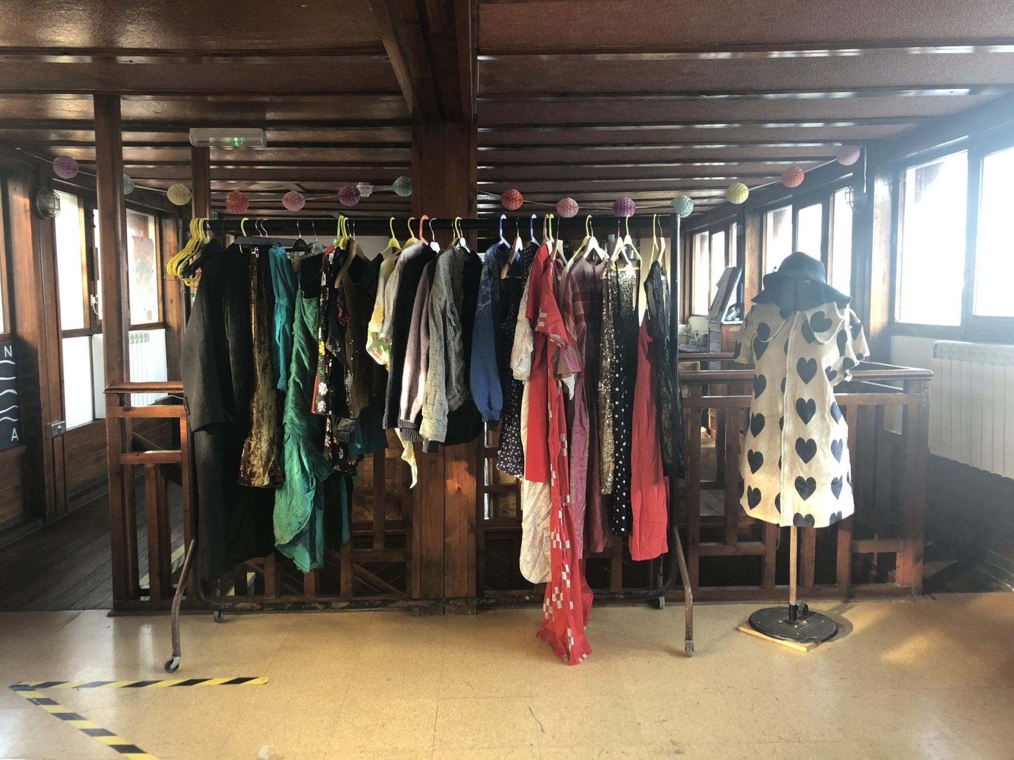 A photograph of a clothes rail with different colourful clothes hanging on it.
