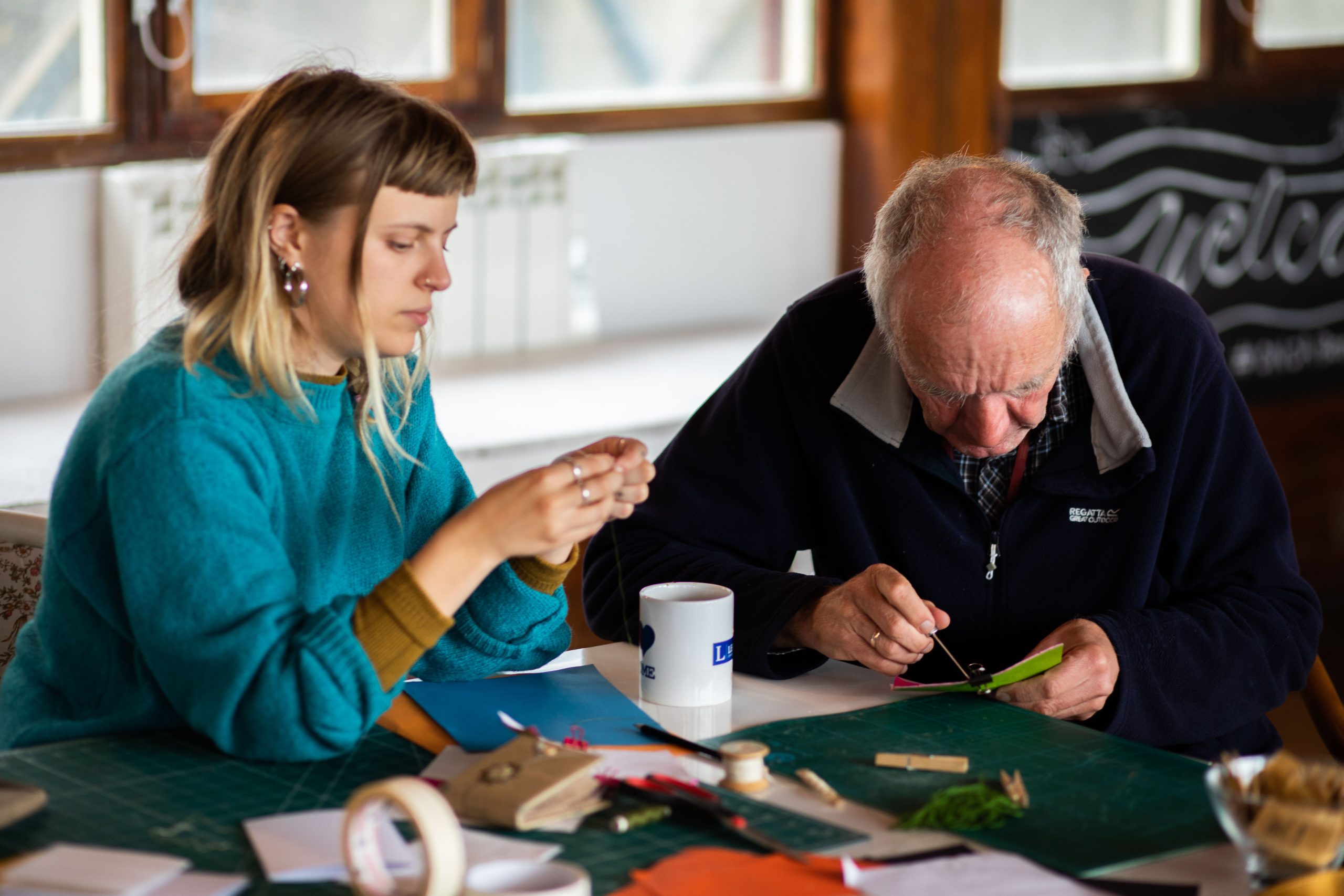 A photograph by Phoebe Wingrove of ONCA's community artist and a local person making books together at community afternoon.