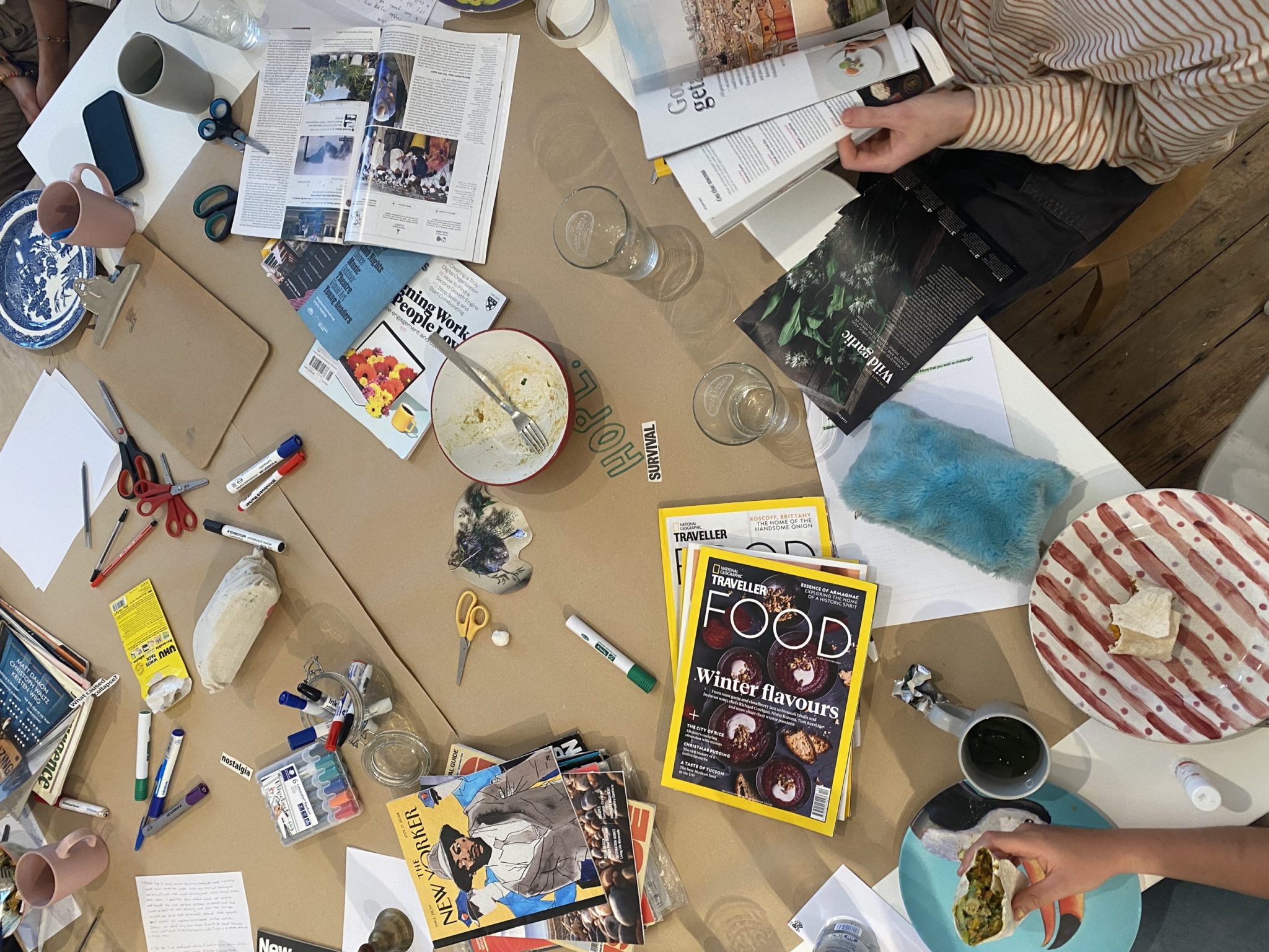 A photograph of people making collages and eating food.